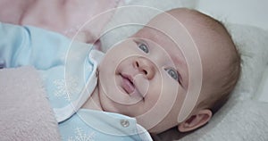 Little cute newborn baby lies on her back in the crib.