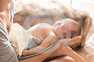 Little cute newborn girl wearing a diaper sleeping on mother lap