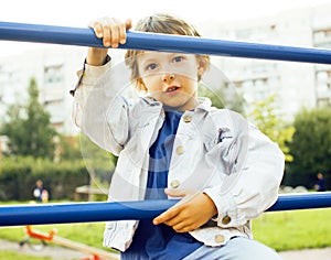 Little cute boy playing on playground, hanging on gymnastic ring