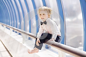 Little cute red hair girl sits on handrail in