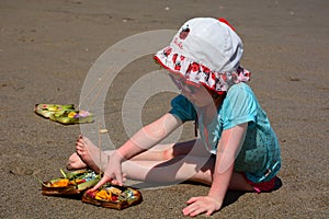 Little cute redhead child plays with sand on Bali beach