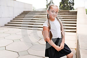 Little cute school girl in school uniform near school building