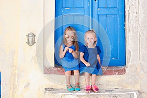 Little cute sisters sitting near old blue door in