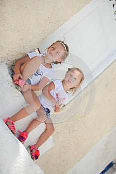 Little cute sisters sitting near old house in