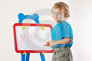 Little cute smiling boy wrote the word mom