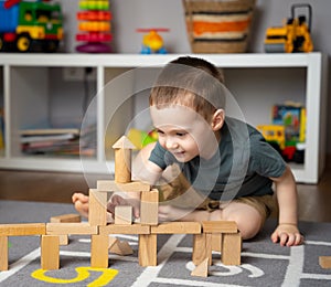 Little cute toddler boy 2,5 years playing wooden blocks in a home children\'s room.
