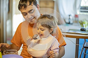 Little cute toddler girl eating ice cream popsicle sitting on daddy lap