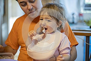 Little cute toddler girl eating ice cream popsicle sitting on daddy`s lap