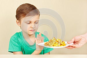 Little cute unhappy boy refuses to eat fried potatoes