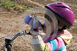 Little cyclist girl drinking photo
