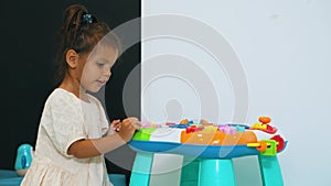 little dark-haired girl enjoying the toy at the nursery, medium shot, kids concept