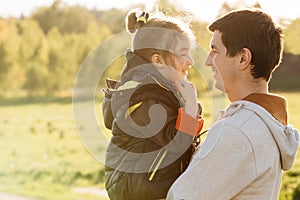 A little daughter in the arms of her father, happy and laughing, playing with her father.