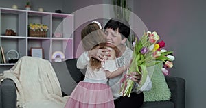 Little daughter congratulates her elderly mother on Mother`s Day. A little girl hugs her mom, smiles and says gentle