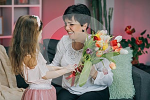 Little daughter congratulates her elderly mother on Mother`s Day. A little girl hugs her mom, smiles and says gentle