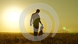 Little daughter and dad walk around field holding hands. child holds father`s hand. dad and baby are resting in the park