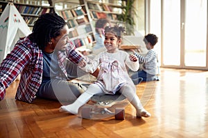 A little daughter enjoys riding a skateboard with her father at home. Family, together, love, playtime