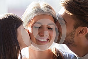 Little daughter and father kissing smiling mother wife on cheeks