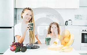 Little daughter and her happy mother drinks green smoothie. Natural antioxidant. Healthy Green food. Mother and daughter