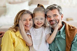 Little Daughter Hugging Parents Sitting Posing At Home