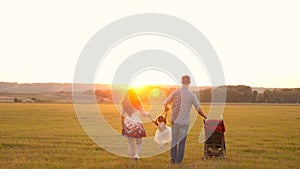 Little daughter jumping, holding hands of dad and mom in park against backdrop of sun. healthy family. child plays with