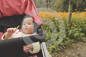 Little daughter lie in baby carseat, eating sugar photo