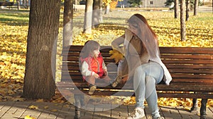 Little daughter and mother play in autumn Park on bench. The concept of happy childhood. baby and mother play with