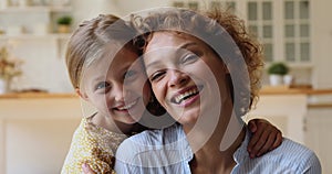 Little daughter piggybacks cheerful mom family smiling looking at camera