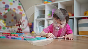 Little daughter plays with toys on the floor, develops fine motor skills. Little daughter learning lifestyle to insert