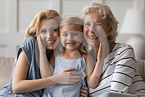 Little daughter posing for photo with old grandmother and mother