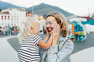 The little daughter touches and hugs her mother's face with her palms. Love of mother and child.