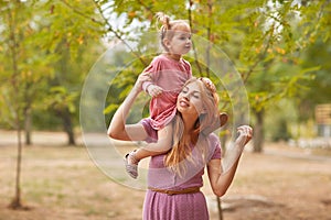 A little daughter walks with mom in the park.