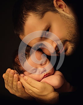 Little 15 days old baby lying securely on his Dad`s arms, against a black background