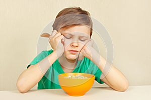Little discontented boy does not want to eat cereal