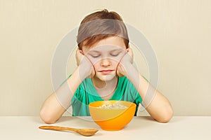 Little displeased boy does not want to eat porridge