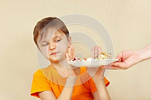 Little displeased boy refuses to eat pasta with cutlet