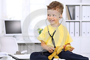 Little doctor examining a ntoy bear patient by stethoscope