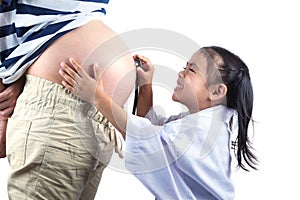 Little doctor listening with stethoscope for his unborn brother in his pregnant mothers belly