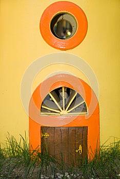 The little door and round window in a yellow wall