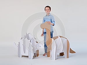 Little dreamer boy playing with a cardboard dinosaurs Brontosaurus and Ankylosaurus. Childhood. Fantasy, imagination.