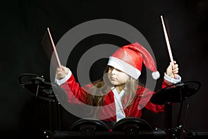 Little drummer disguised as Santa Claus playing the elettronic drum kit