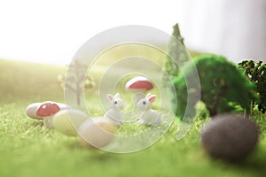 Little Easter bunny toys and Easter eggs on green grass. Fairy tale