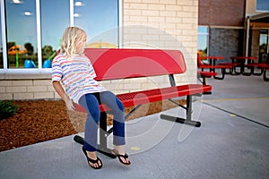 Little Elementary School Aged Child Sitting Alone on A Buddy Bench at School