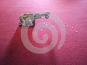 Little elephant bronze sculpture on red floor carpet inside temple offering coins