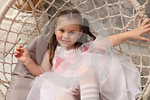 Little emotional girl rides on a swing in the children& x27;s room. Happy child 4-5 years old close-up. A little girl in