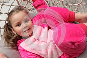 Little emotional girl rides on a swing in the children& x27;s room. Happy child 4-5 years old close-up. A small child