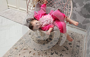 Little emotional girl rides on a swing in the children& x27;s room. Happy child 4-5 years old close-up. A small child