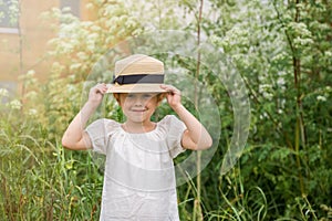 Little emotional Girl in a white boho dress with a hat smiling playing