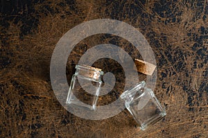 Little empty glass bottles with cork on abstract wooden background. Top view