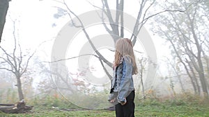 Little European girl with a long hair, blue jacket, black pants, sneakers and blue eyes. A frightened little child is standing in