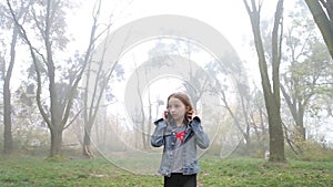 Little European girl with a long hair, blue jacket, black pants, sneakers and blue eyes. A frightened little child is walking thro